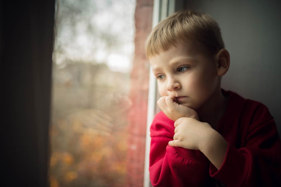 Грустный ребенок возле окна